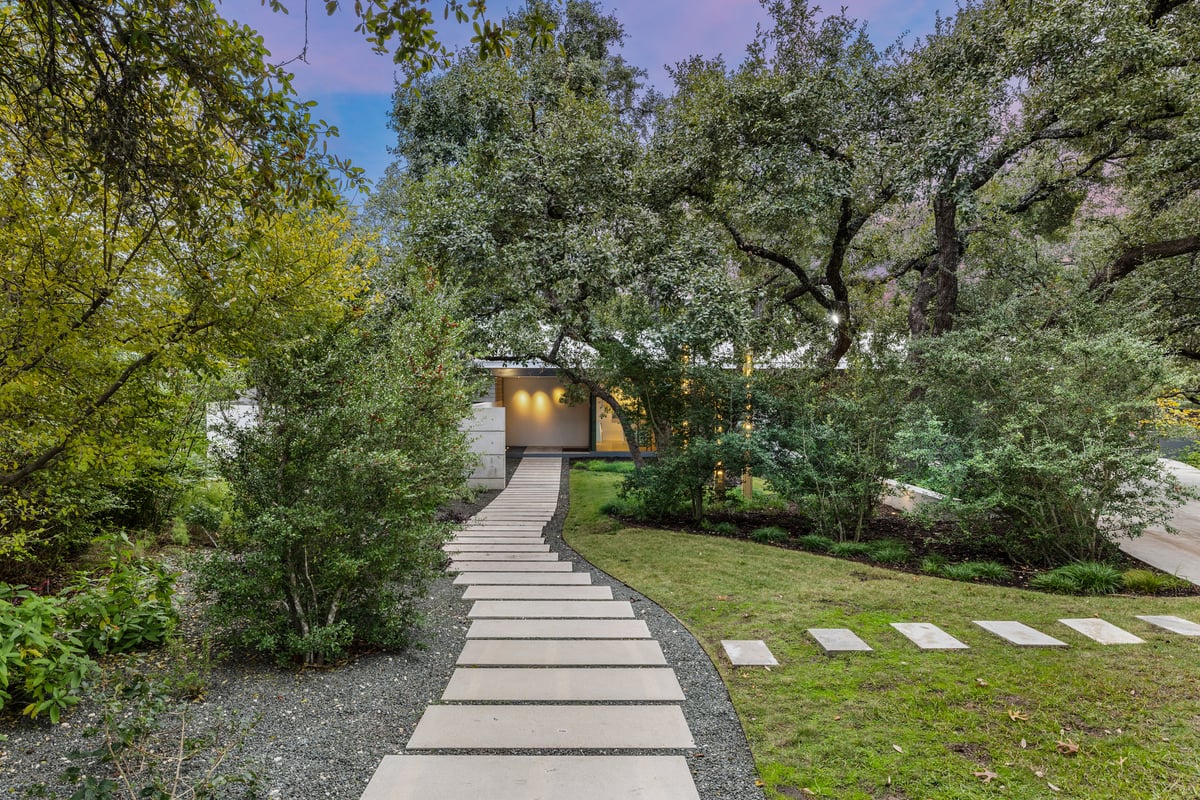 Curving garden path through native plantings toward the house under the oak canopy