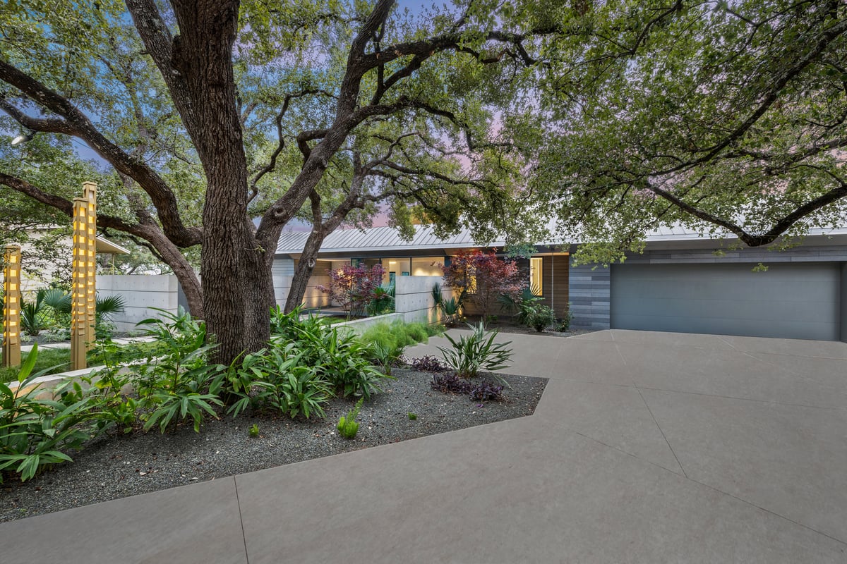 Motor court beside a large live oak with a planted island and the garage beyond