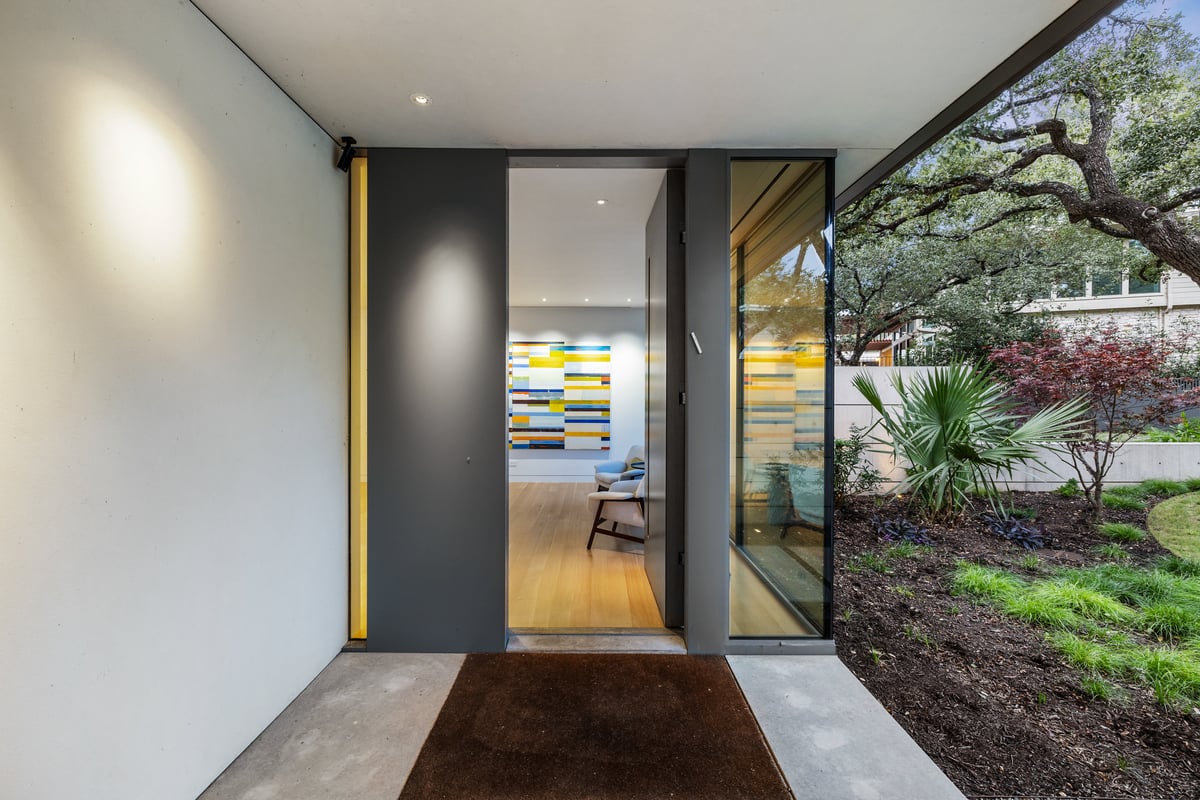 Pivot front door set in a glass entry with a view through to the garden
