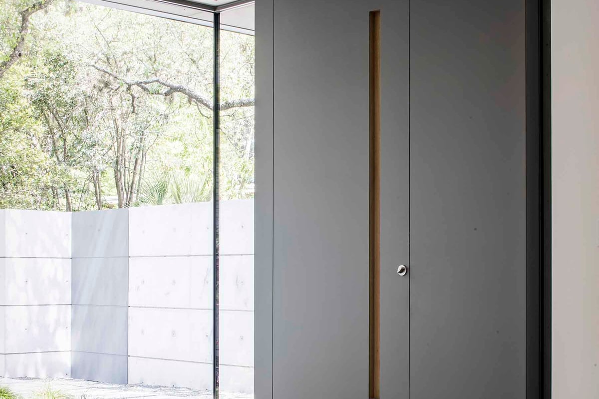 A tall pivot door opening from a walled garden into the house