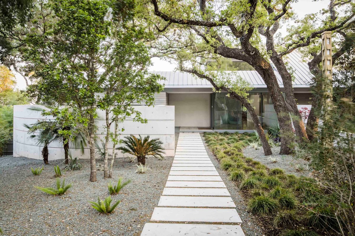 Paver walk through a gravel garden under live oaks to the entry