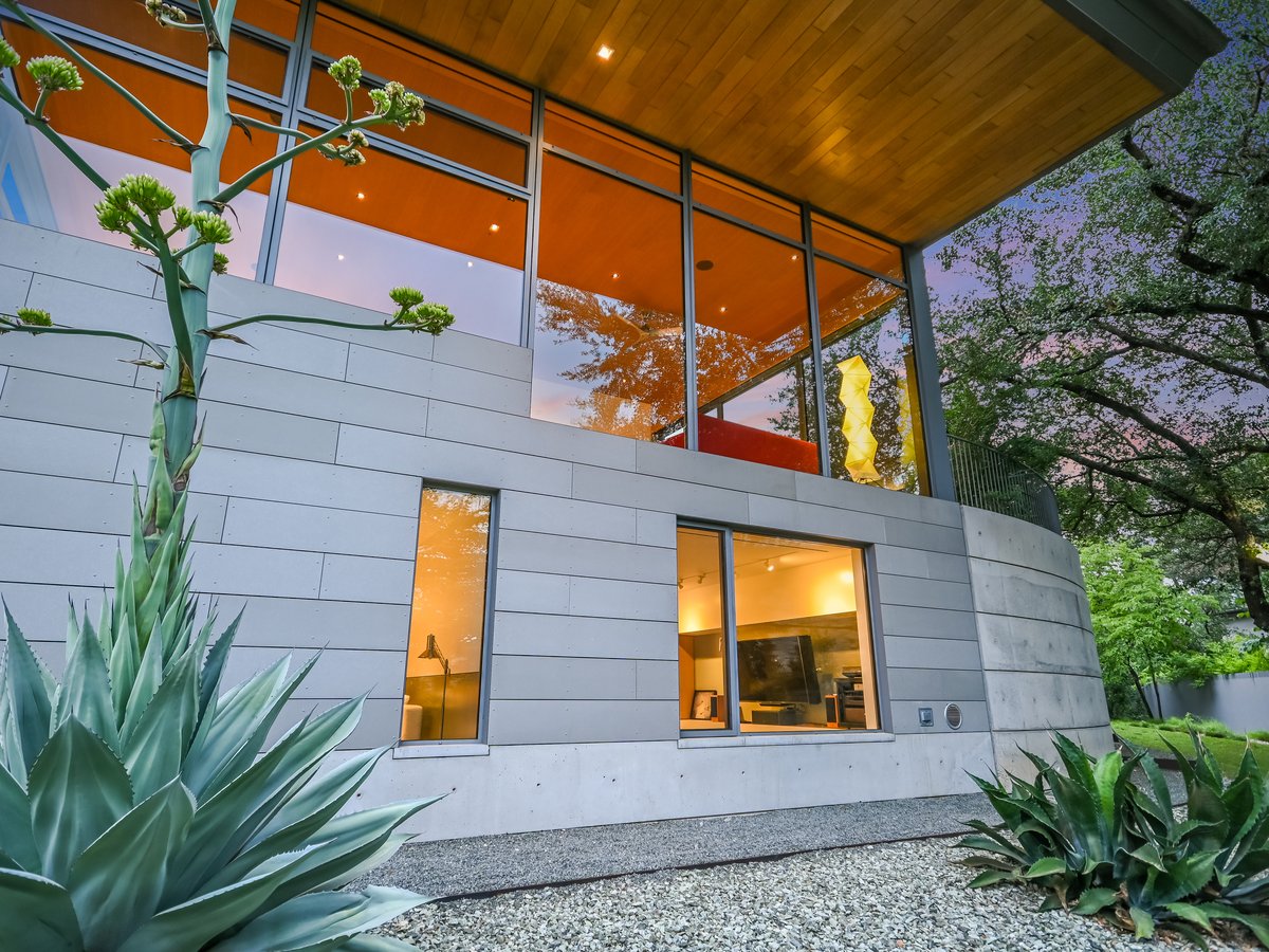 Upper level glass glowing at dusk above a planted bed