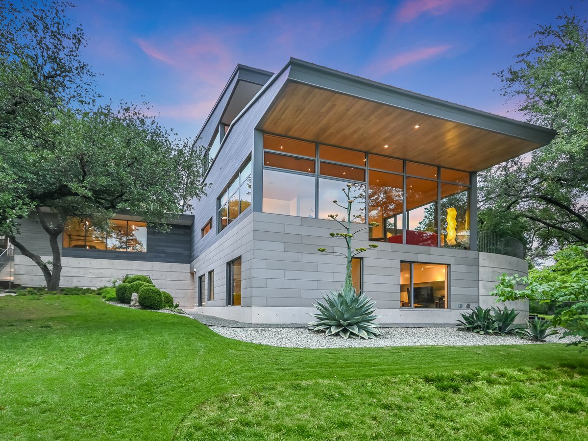 The rear of the house at twilight, the cantilevered upper floor over the lawn