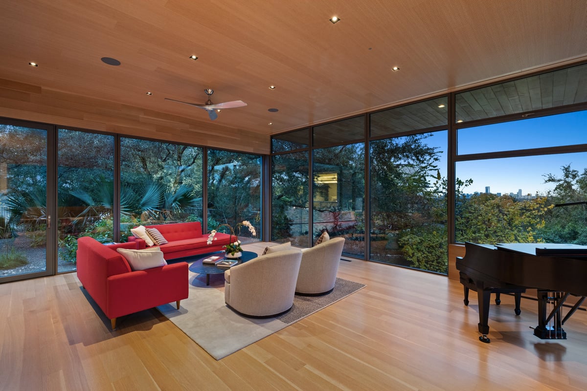 Great room with a grand piano, floor-to-ceiling windows and a warm wood ceiling