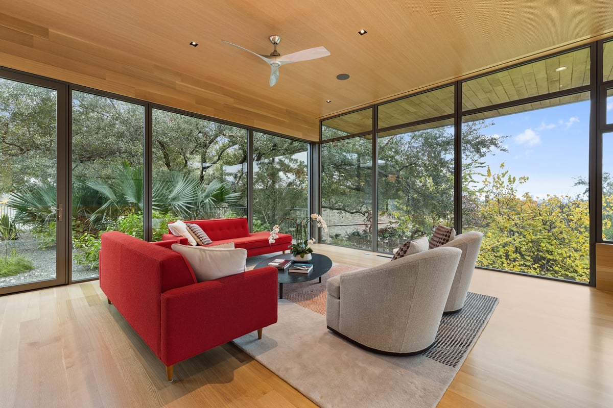 Corner of the great room where two glass walls meet the tree canopy