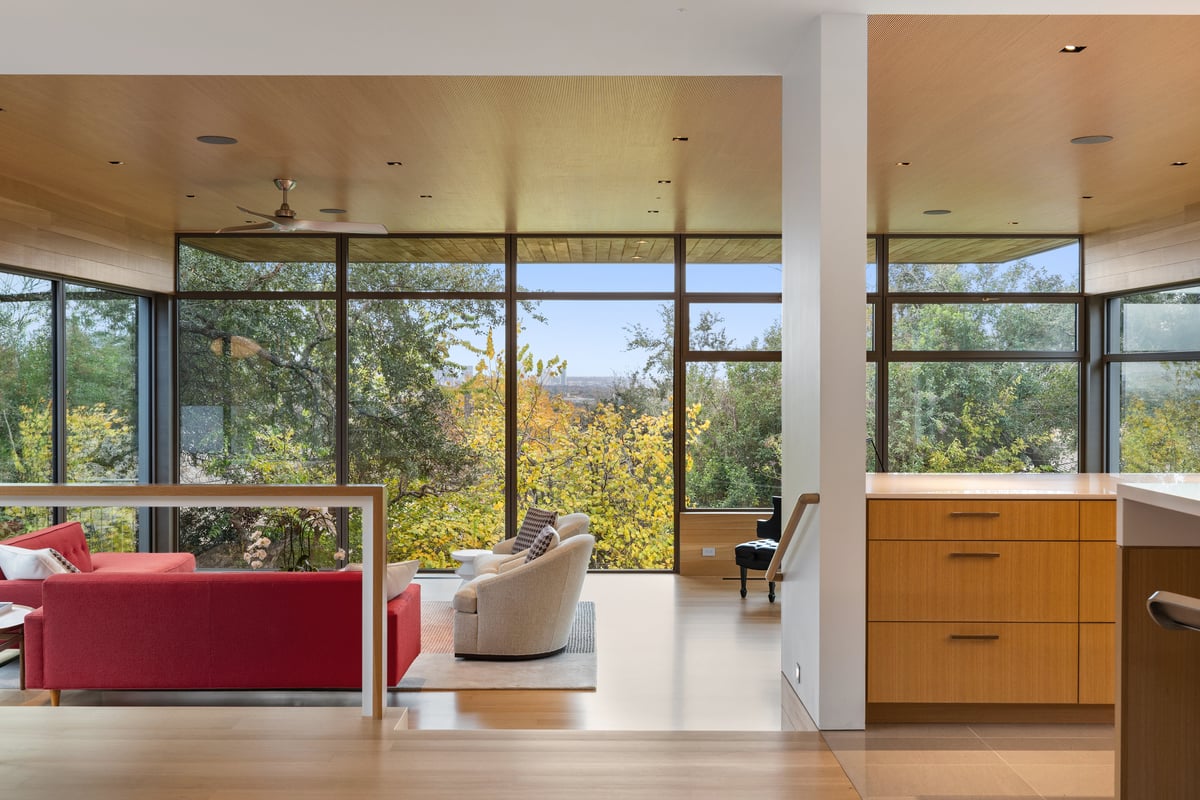 The great room seen from the kitchen, red sofa and swivel chairs against the glass