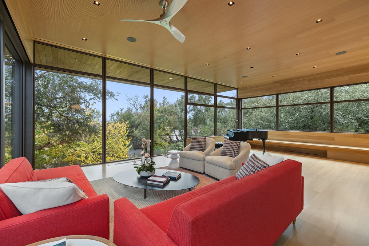 Great room with two red sofas, swivel chairs and a grand piano in the far corner
