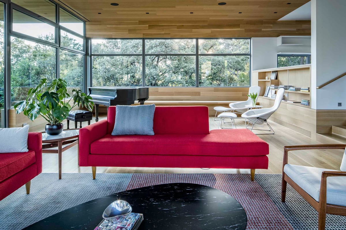 Great room with a red sofa, a dark round table and glass on two sides