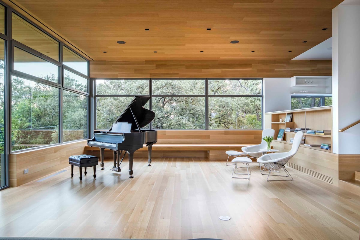 Grand piano in the glass corner of the great room under the wood ceiling