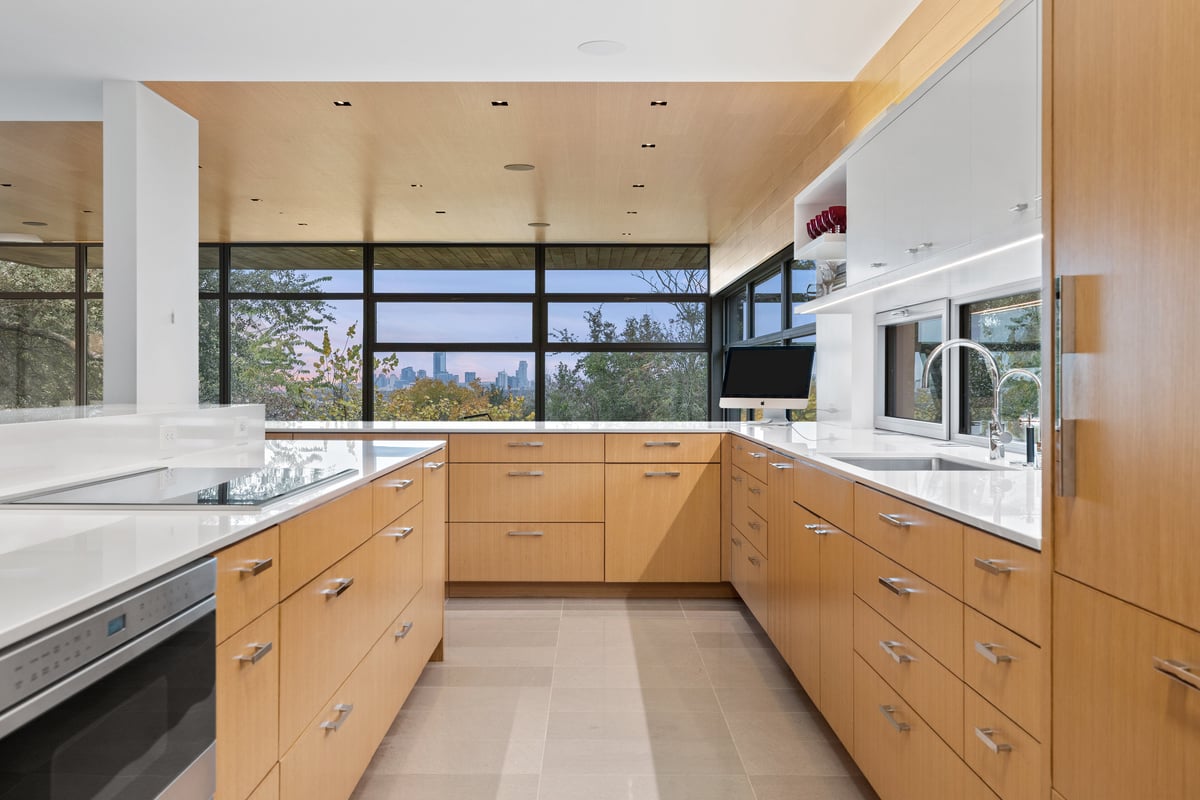 Kitchen with an island cooktop, rift oak cabinetry and a ribbon window
