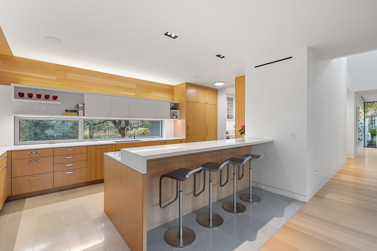 Kitchen seen from the dining area, bar stools at a white island