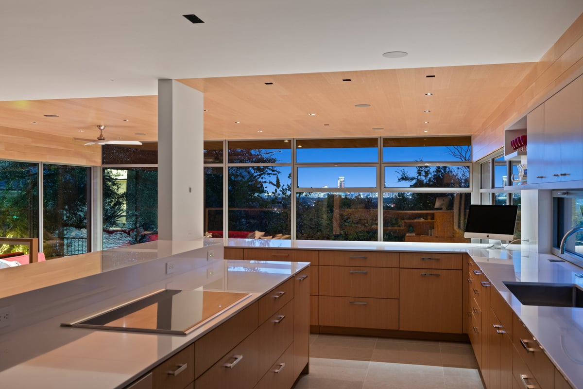 Kitchen island cooktop facing a ribbon window with the downtown skyline over the trees