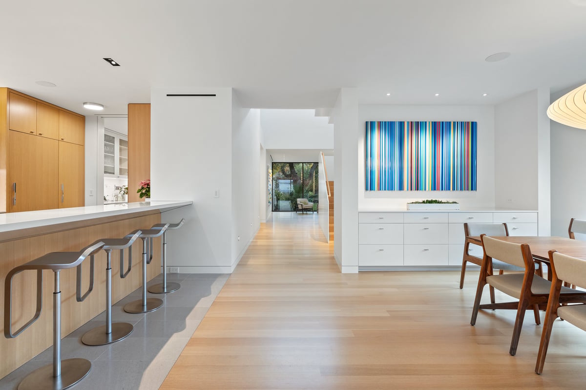 Kitchen bar seating with the dining room and striped artwork beyond