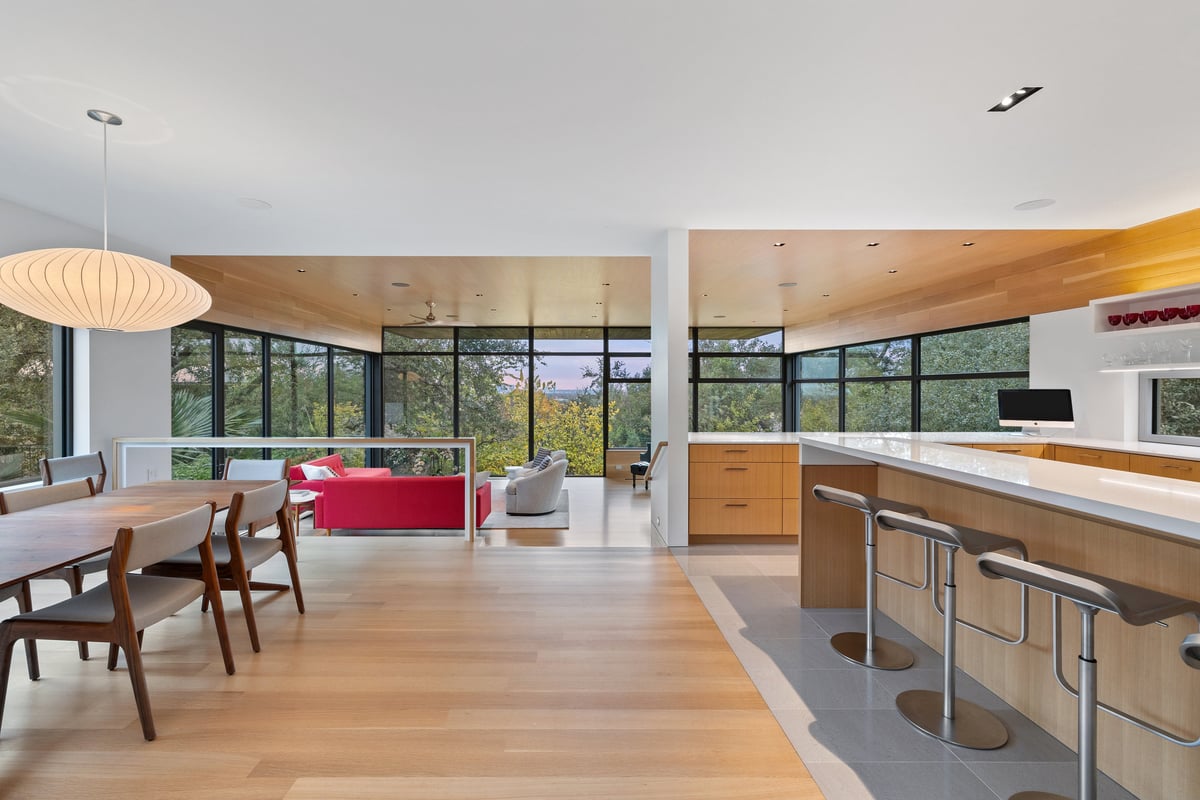 Dining table and kitchen island opening to the great room and its glass walls