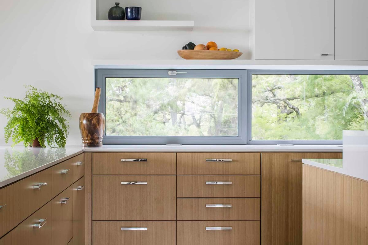 Kitchen counter under a wide window to the trees, oak drawers below