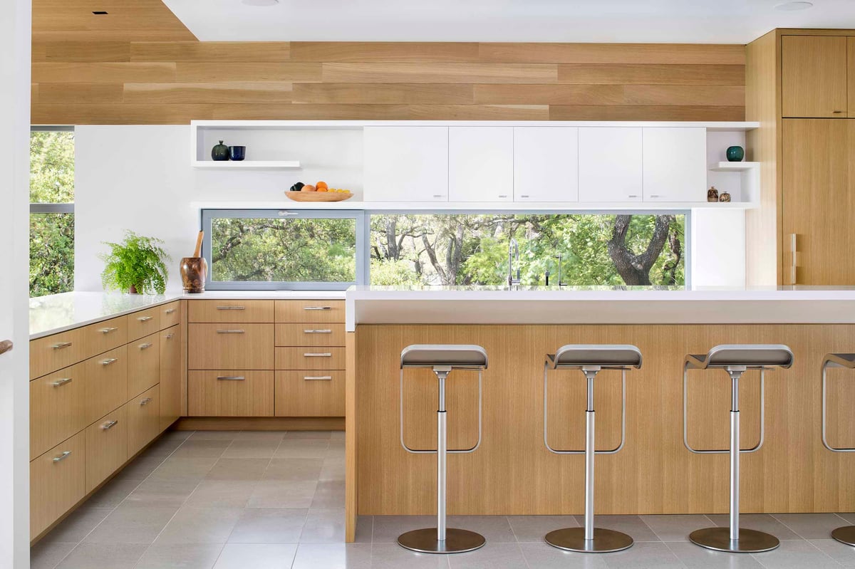 Kitchen bar with four stools, oak cabinets and a ribbon window
