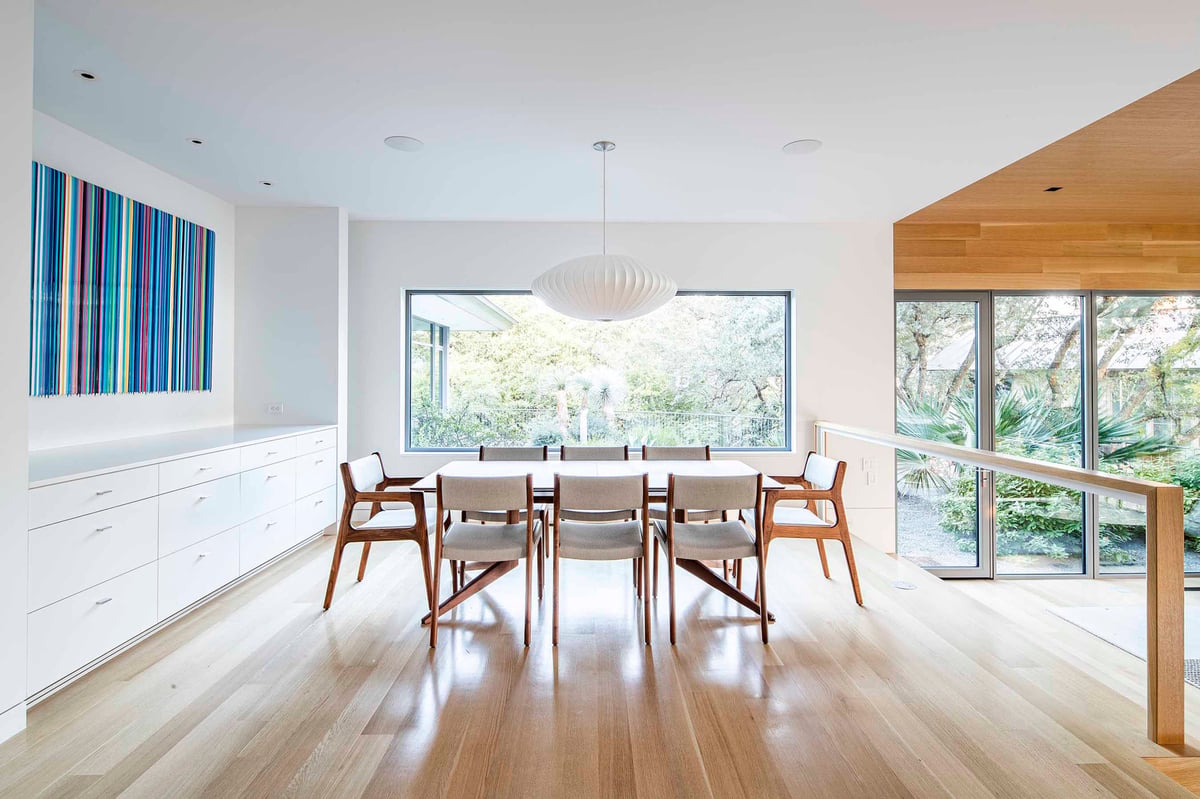 Dining room with white built-ins, a striped artwork and a window to the trees