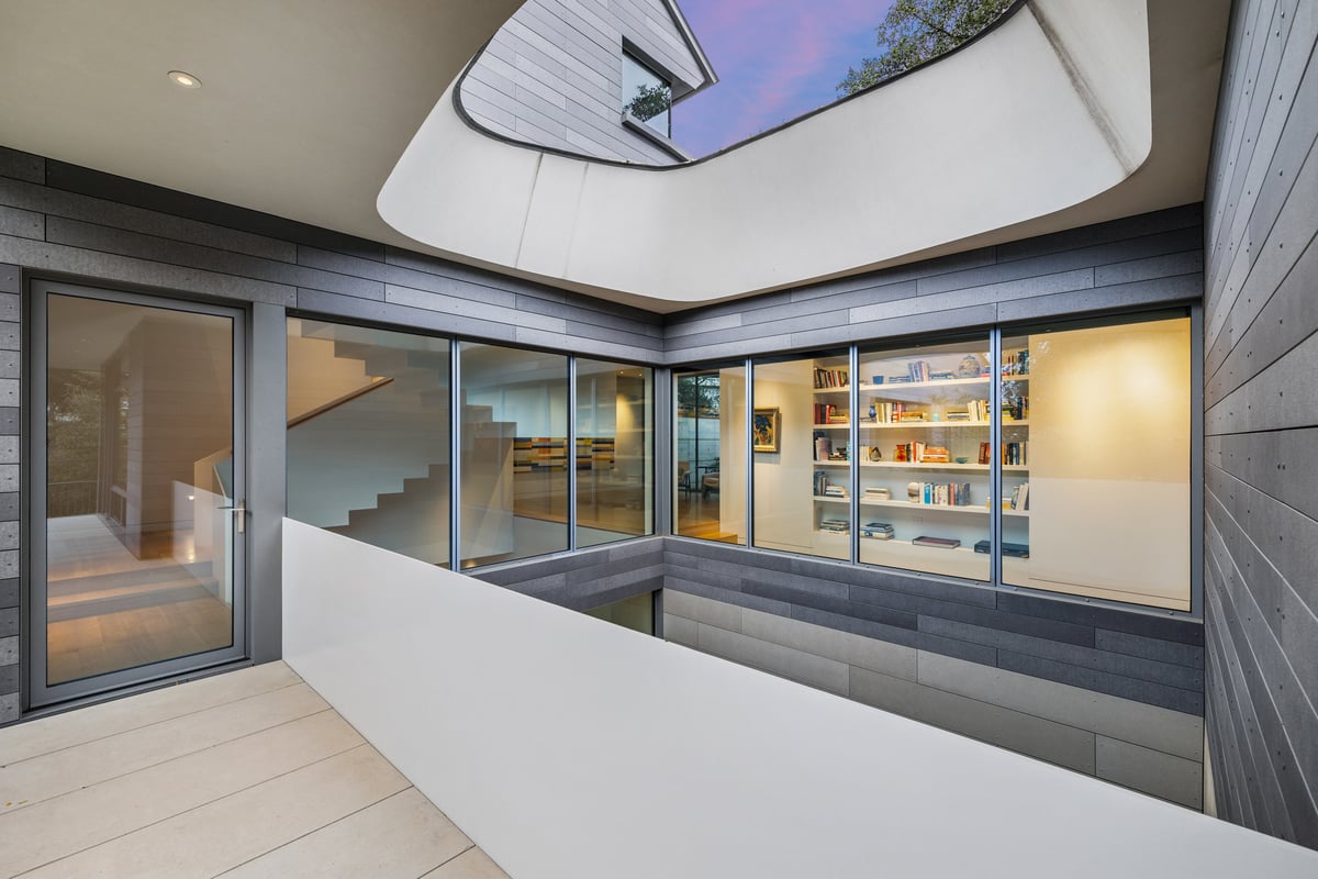 Entry hall under a skylight, with glass walls opening to the courtyard and a built-in bookshelf beyond