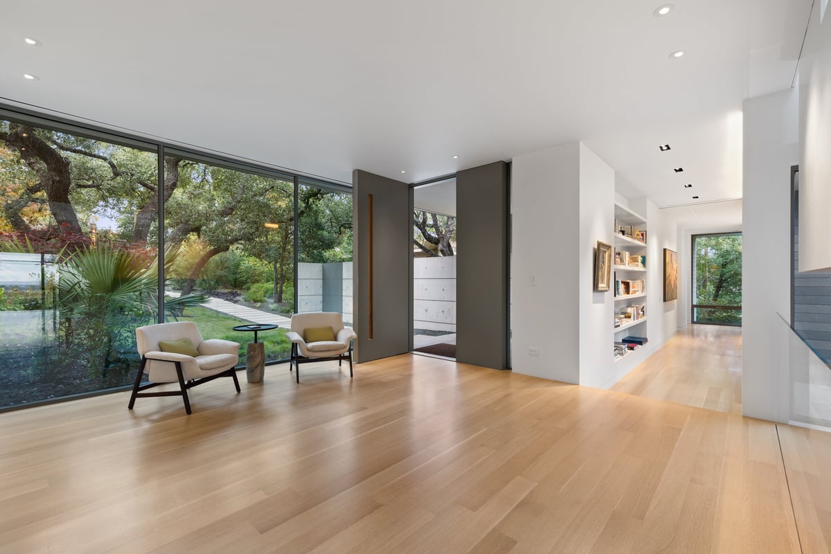 Entry hall with a tall pivot door, white oak floors and glass to the garden