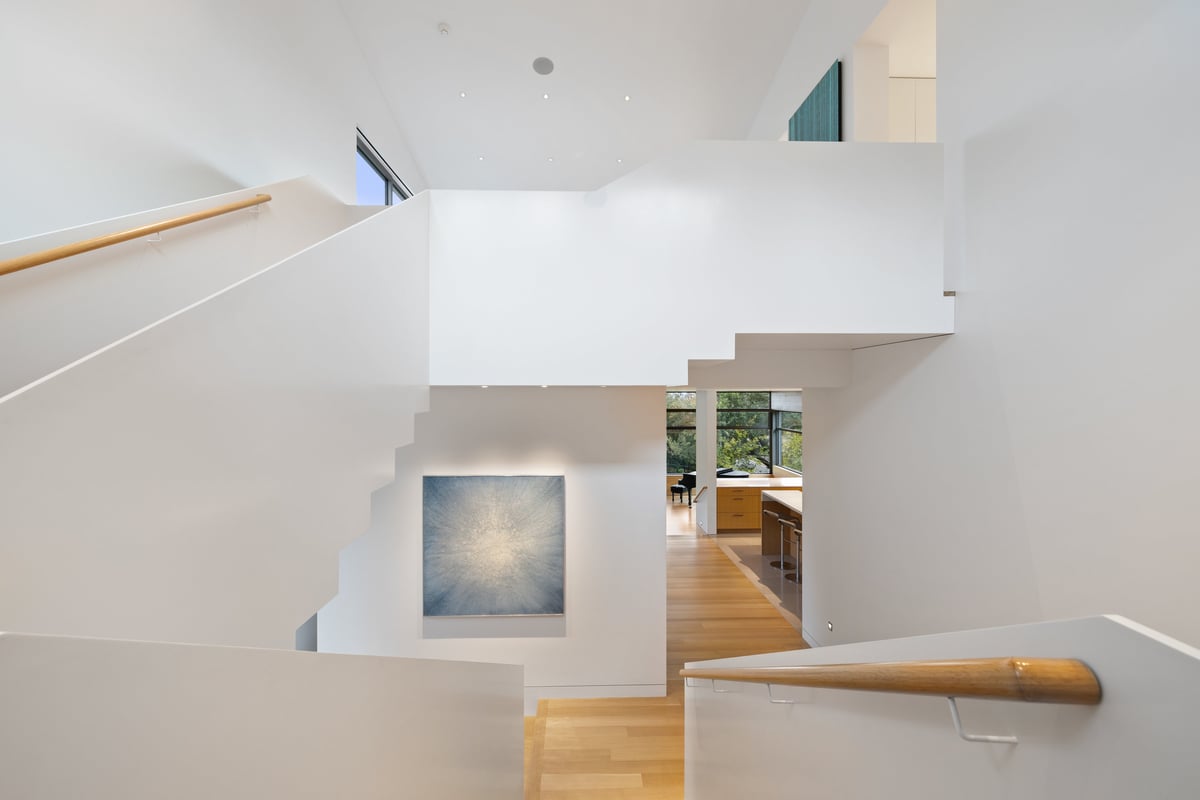 White stair landings seen from above, with a framed artwork on the lower wall