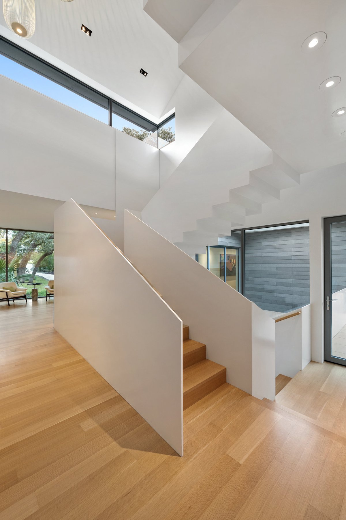 The open stair in portrait, white stringers and oak treads under a skylight