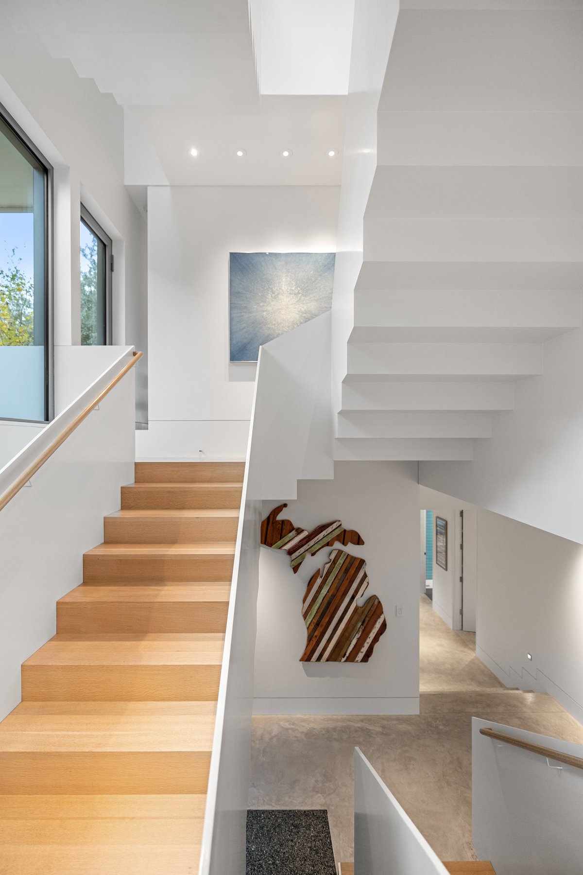 A run of oak stair treads beside a white wall and a sculptural artwork