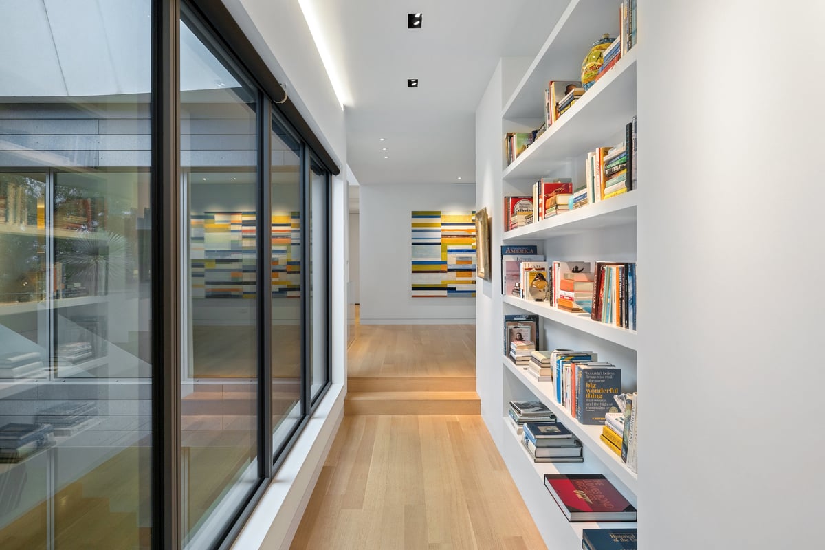 Hall lined with full-height bookshelves beside a wall of glass