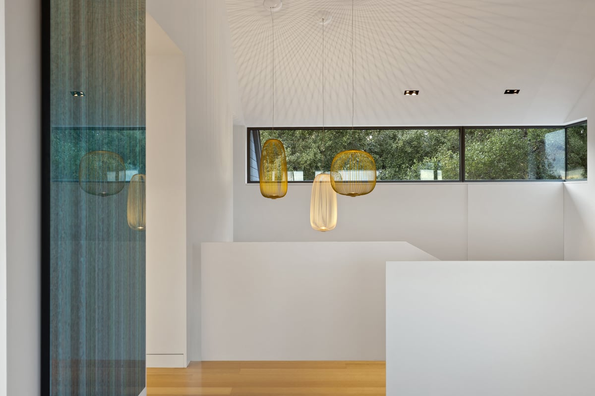 Amber glass pendants hanging beside a clerestory window and a white wall