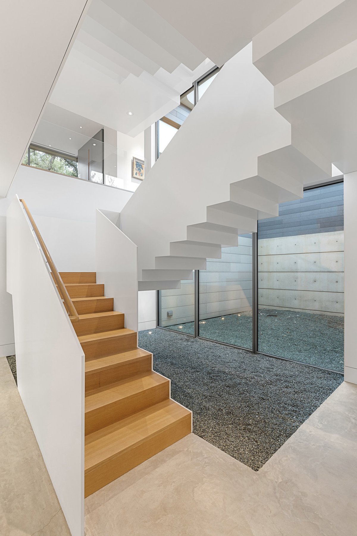 Oak stair descending beside a glass wall to a gravel light well