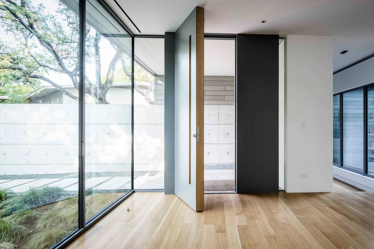 Entry hall with a glass wall to the garden and a dark pivot door