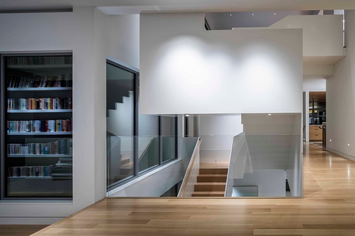 A library wall and glass stair rail beside the open stair