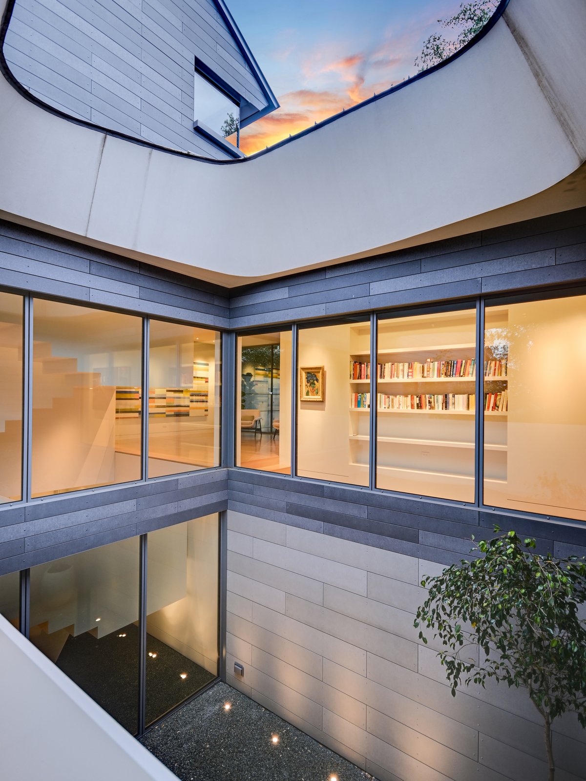 The courtyard oculus seen from below, glass walls and lit shelves around it
