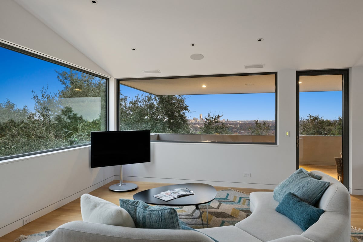 Upstairs lounge with a curved sofa and a long window framing the downtown skyline