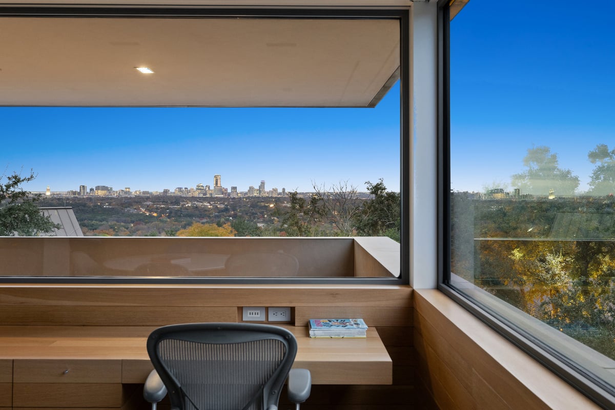 Built-in desk under a corner window with a wide view of the city skyline