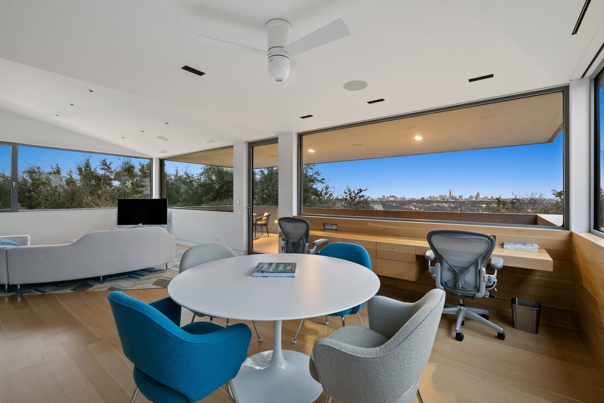 Upstairs study with a round table, blue chairs and windows on two sides
