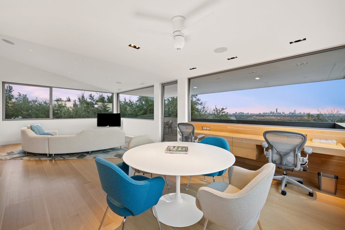 Upstairs study and lounge at dusk with the skyline along the windows