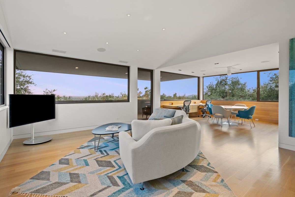 Upstairs lounge with a curved sofa on a patterned rug, study beyond