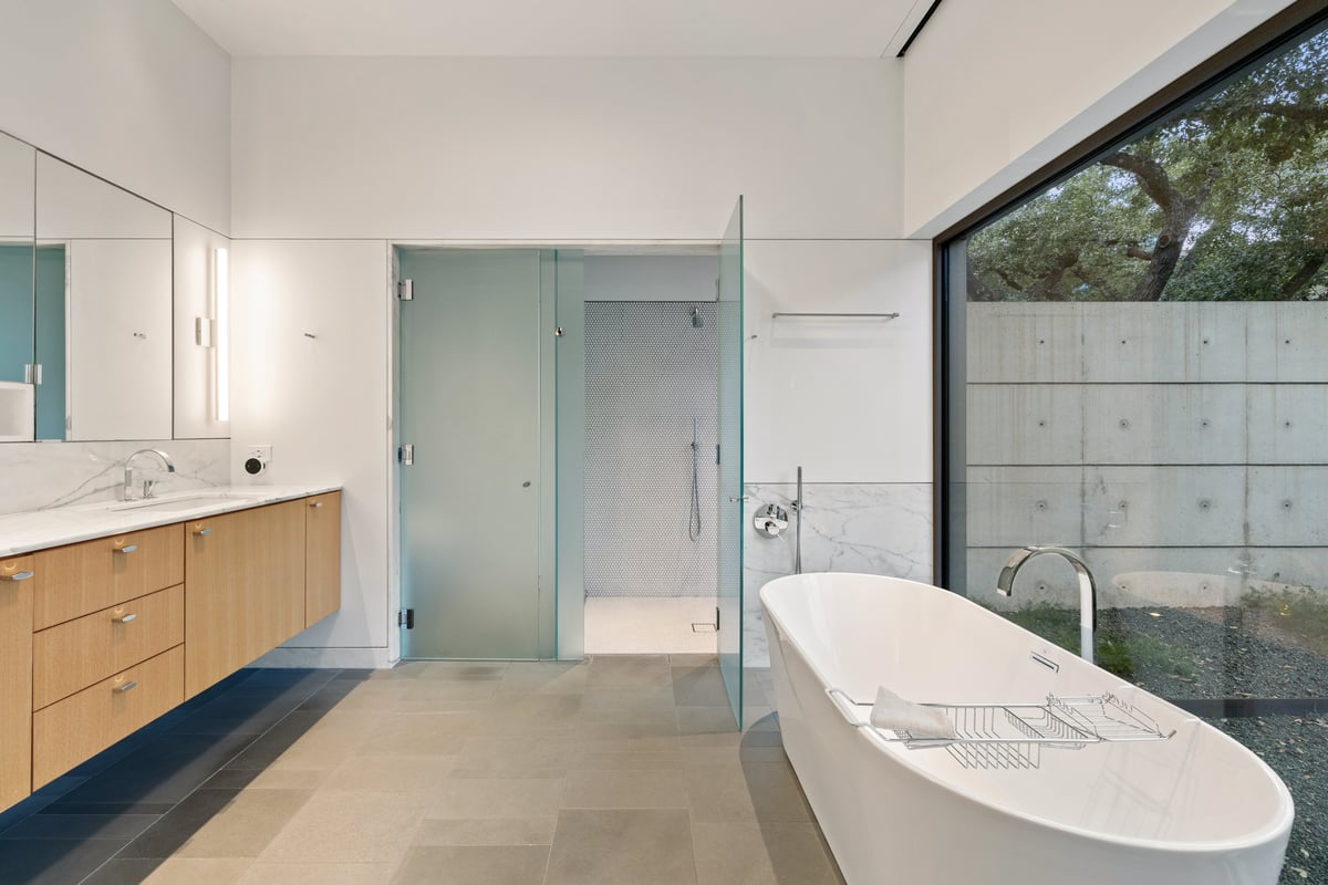 Primary bath with a freestanding tub, double vanity and a private walled garden