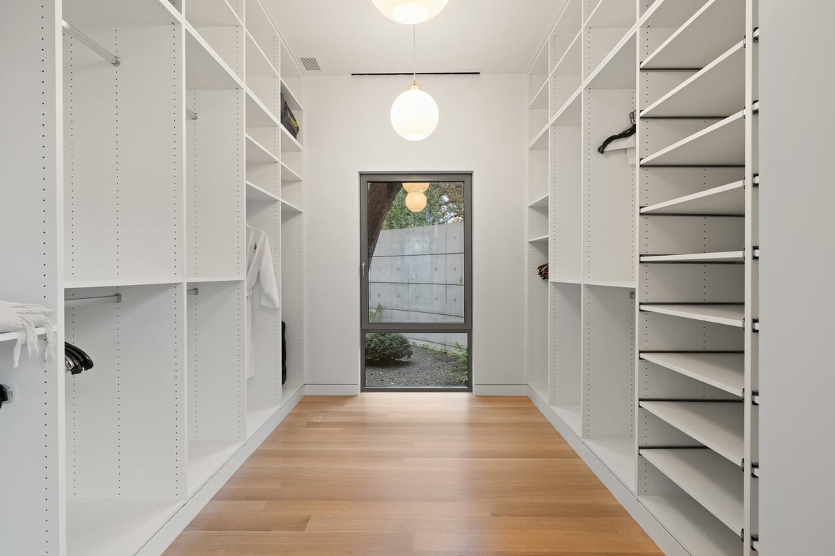 Primary closet with open shelving and a glass door to a walled garden