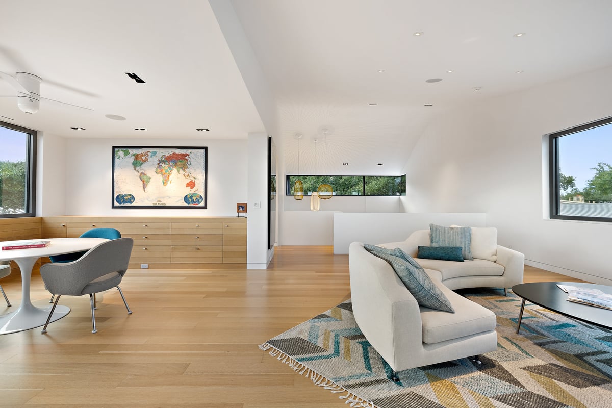 Lower level family room with a curved sofa, a round table and a world map