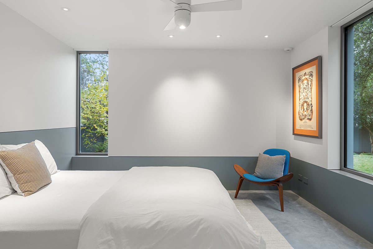 Guest bedroom with a reading chair beside a tall narrow window