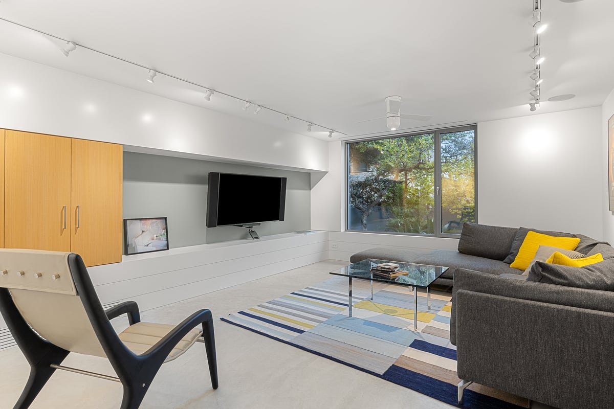 Lower level media room with a sectional sofa and a window to the garden