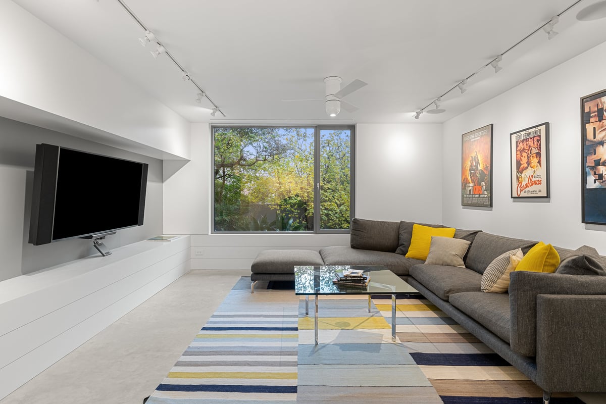 Lower level media room seen wide, framed posters along the wall