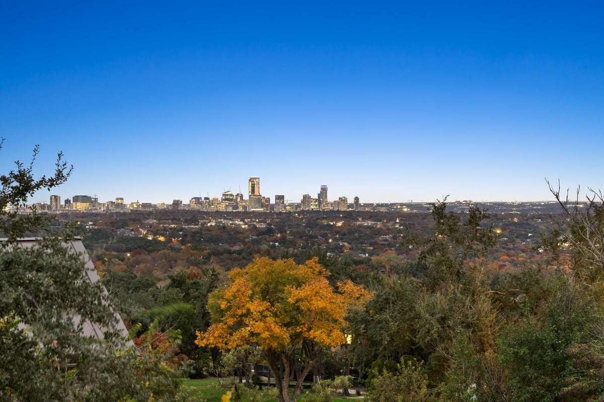 Downtown Austin skyline at dusk above autumn color in the tree canopy