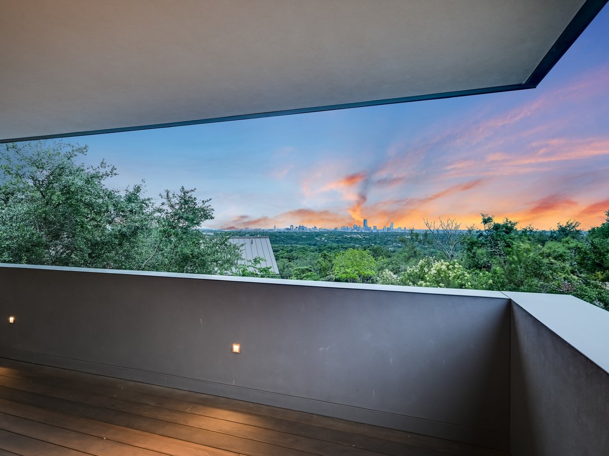 Terrace wall framing a pink and orange sunset over the treetops