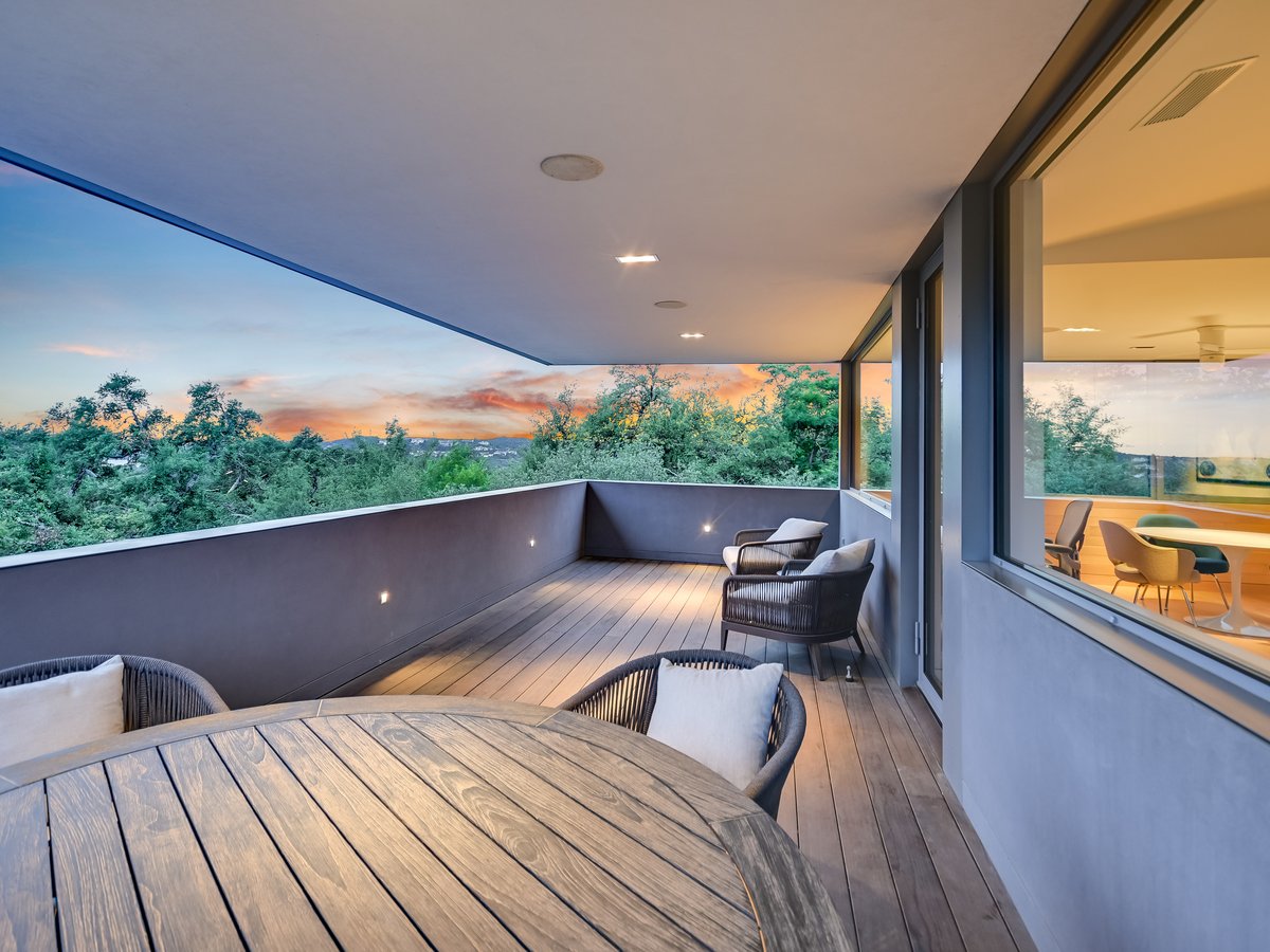 Round terrace table and chairs at dusk beside the lit interior