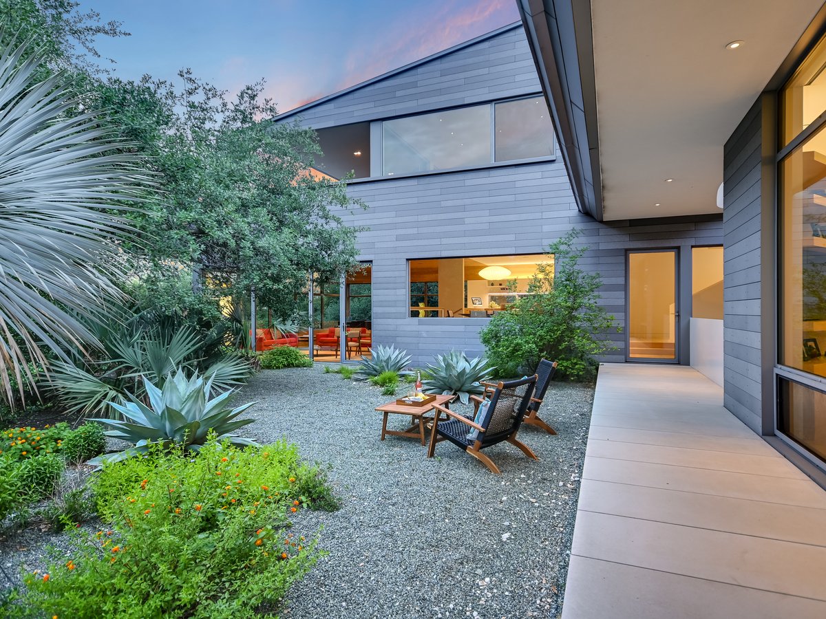 Courtyard garden at dusk with chairs, agaves and lit windows