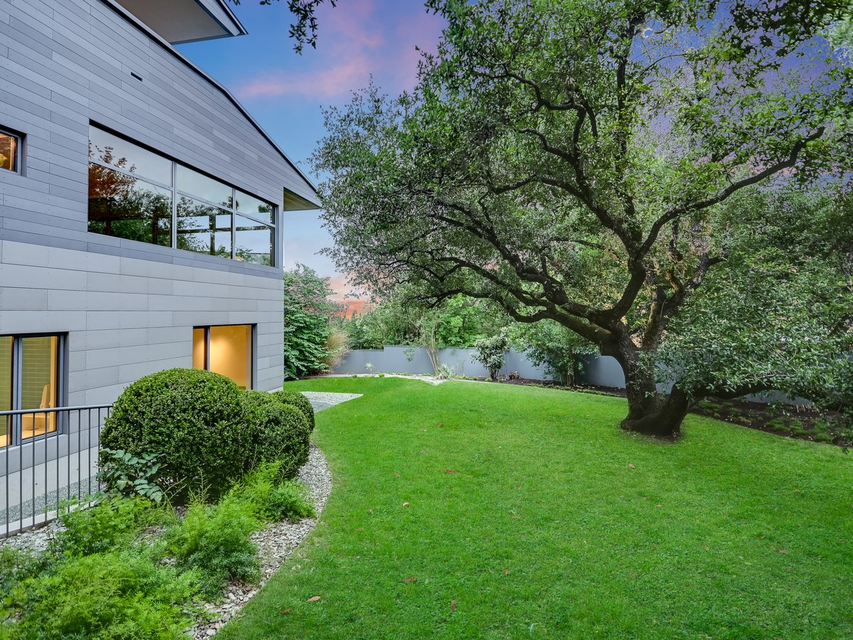 Rear lawn beside the house with a large live oak