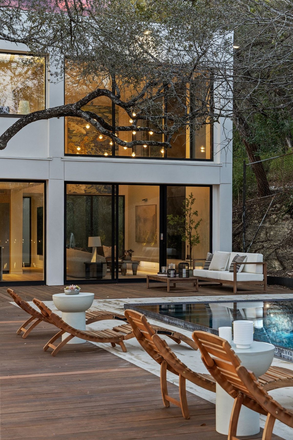 The pool terrace and two-story glass facade at dusk