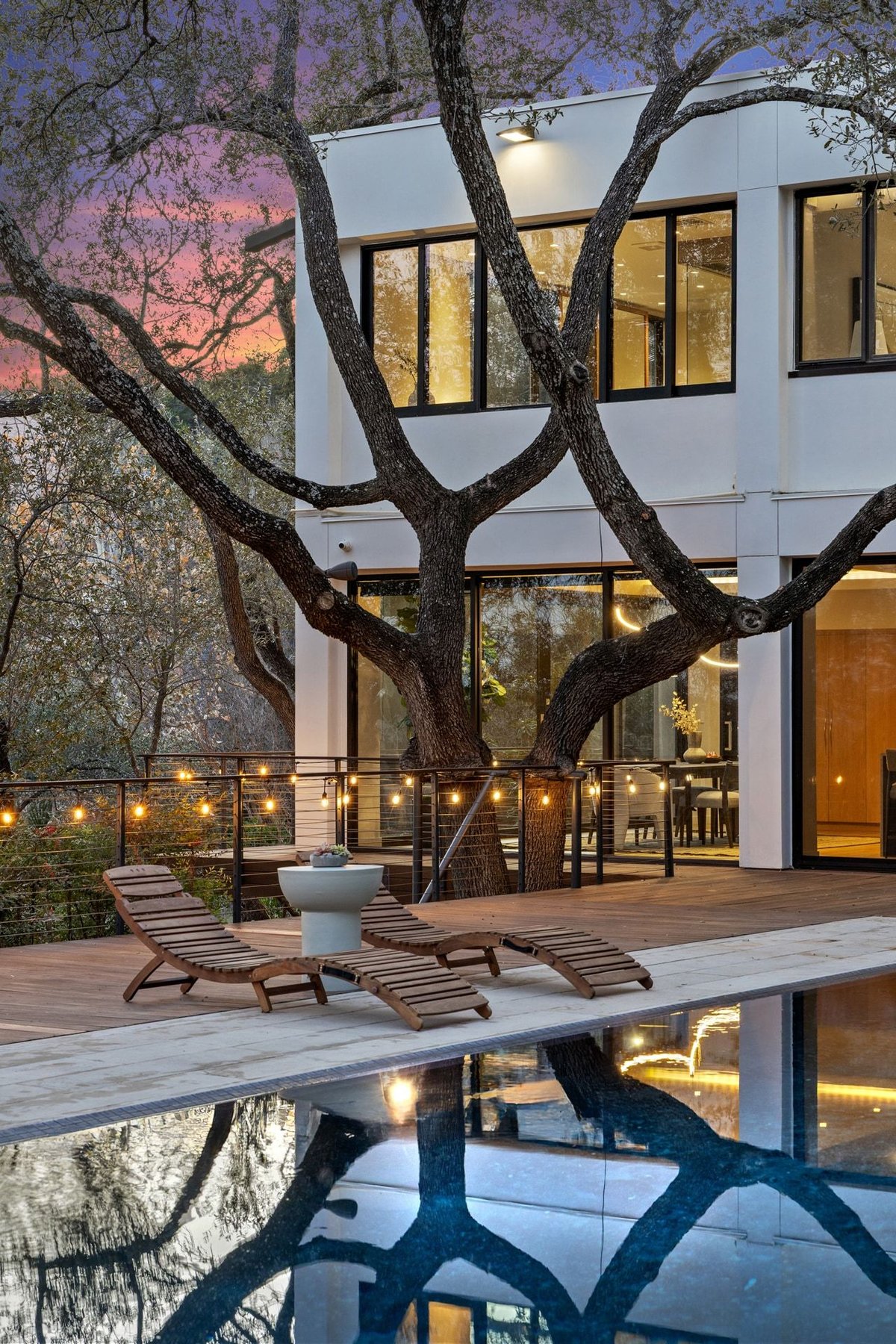The pool reflecting the lit house and string lights at dusk